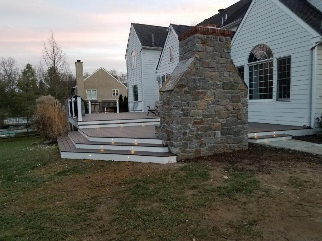 A backyard deck on the house with white siding.