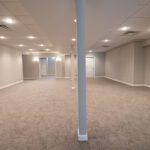 A finished basement with new carpeting and beautiful overhead lighting.