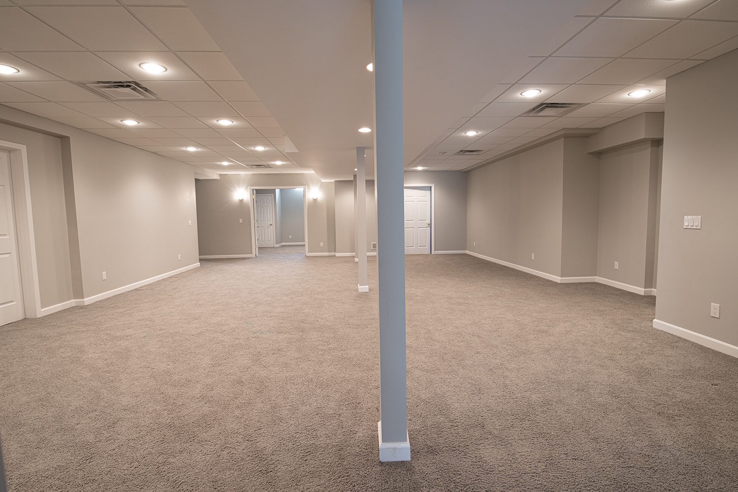 A finished basement with new carpeting and beautiful overhead lighting.