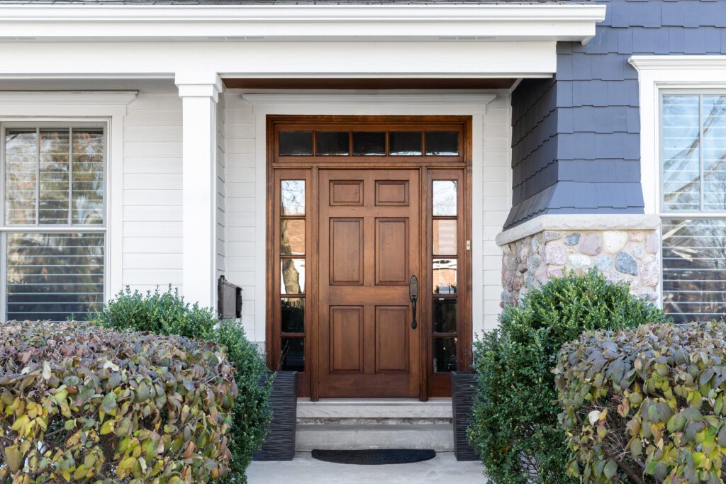 A wooden front door surrounded by windows